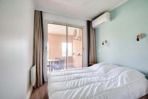 un lit blanc dans une chambre avec une fenêtre dans l'établissement Village Pont Royal en Provence - maeva Home - Appartement cosy et climatisé 2 pièces 4 personnes - Sélection - super Home MAE-2154, à Mallemort