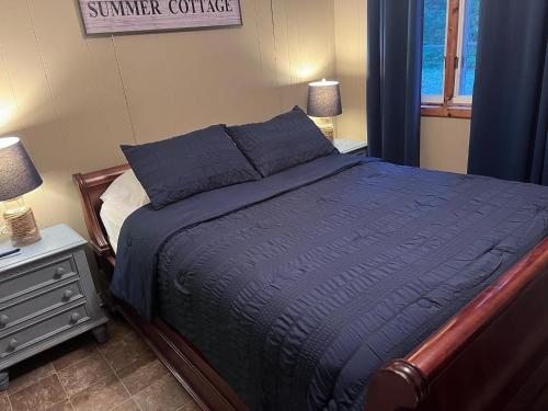 een slaapkamer met een bed met een blauw dekbed en een raam bij The “Loon” waterfront Muskoka cottage in Utterson