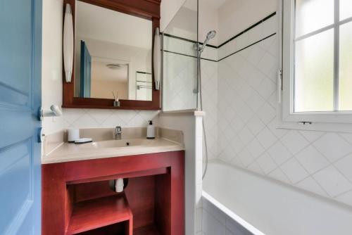 une salle de bain avec un lavabo, un miroir et une baignoire dans l'établissement Les Maisons de Lacanau les Pins - maeva Home - Maison 3 pièces 6 personnes - Prestige MAE-1624, à Lacanau