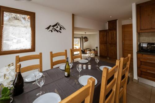 - une salle à manger avec une table, des bouteilles de vin et des verres dans l'établissement Chalet Lova, à Valloire
