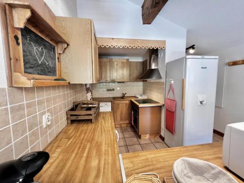 une cuisine avec des armoires en bois et un réfrigérateur blanc dans l'établissement Résidence Les Oursons - Appartement huit personnes au pied des pistes MAE-3894, à Notre-Dame-de-Bellecombe