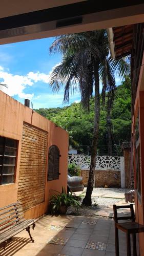 un porche con un banco y una palmera en Seô Hostel - Ubatuba en Ubatuba