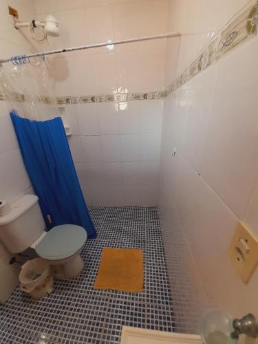 a bathroom with a toilet and a blue shower at Seô Hostel - Ubatuba in Ubatuba