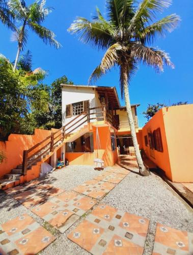 an orange house with a palm tree in front of it at Seô Hostel - Ubatuba in Ubatuba