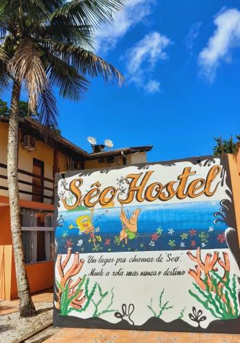 a sign for a seafood hotel with a palm tree at Seô Hostel - Ubatuba in Ubatuba