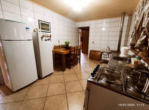 a kitchen with a stove and a refrigerator and a table at Casa do pescador, na rota do Cristo Protetor in Estefânia