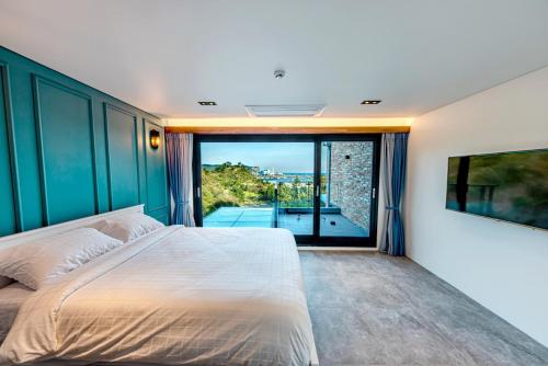 1 dormitorio con cama grande y ventana grande en Ocean Brick Poolvilla, en Seogwipo