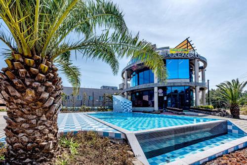 un palmier en face d'un bâtiment avec piscine dans l'établissement Ocean Brick Poolvilla, à Seogwipo