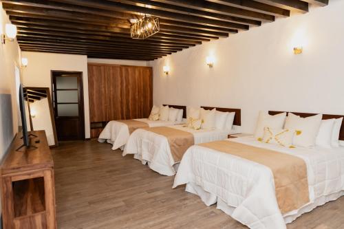 a hotel room with three beds with white sheets at La Casona de Josefa in Querétaro