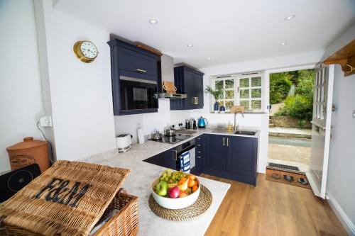 a kitchen with blue cabinets and a bowl of fruit at Fort Victoria Cottages - Spinnakers in Yarmouth