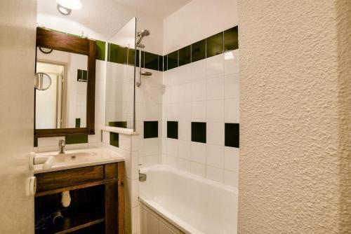 ein Badezimmer mit einer weißen Badewanne, einem Waschbecken und einem Spiegel in der Unterkunft Le Domaine du Golf de Pinsolle - maeva Home - Appartement 2 pièces 5 person 704 in Soustons