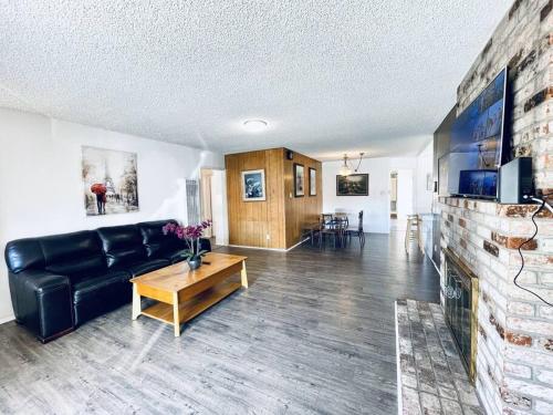 a living room with a black couch and a fireplace at 202 Spacious Hayward Entire 4BR SFH in Hayward