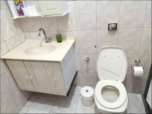 uma casa de banho com um WC branco e um lavatório. em Suíte privativa Gigá em Brotas