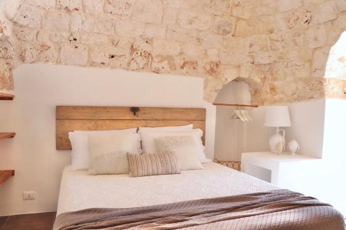 een slaapkamer met een bed en een stenen muur bij Trullo a ll'éra in Ceglie Messapica