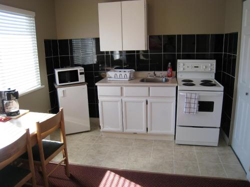 a kitchen with white cabinets and a white stove top oven at Beach Grove Motel in Tsawwassen