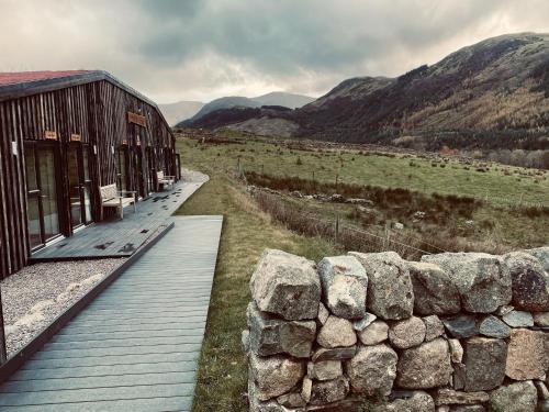 a wooden walkway next to a stone wall next to a building at Ben Nevis Inn Rooms in Fort William