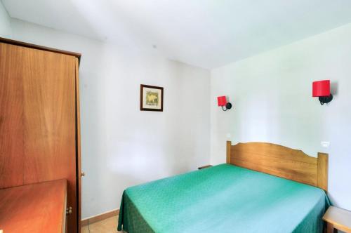 een slaapkamer met een groen bed en een houten deur bij La résidence du Lac - maeva Home - Appartement 2 pièces 4 personnes - Conf 694 in Monflanquin