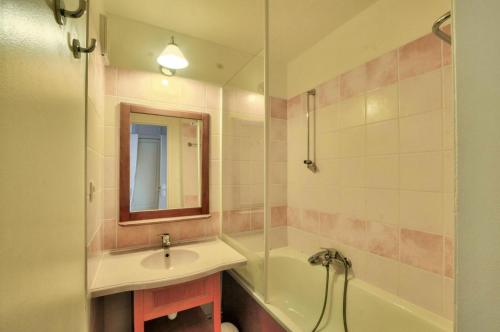 een badkamer met een wastafel, een bad en een spiegel bij La résidence du Lac - maeva Home - Appartement 2 pièces 4 personnes - Conf 694 in Monflanquin