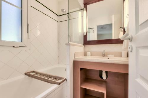 une salle de bain avec un lavabo, une baignoire et un miroir dans l'établissement Les Maisons de Lacanau les Pins - maeva Home - Maison 3 pièces 6 personnes - Sélection MAE-7964, à Lacanau