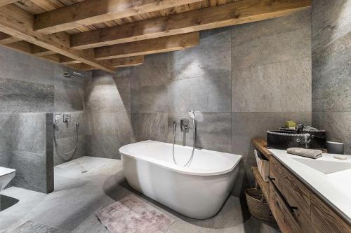 uma casa de banho com uma banheira branca e um lavatório. em Résidence Fontany - Chalets pour 12 Personnes 044 em Les Allues