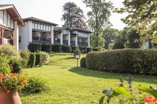 a building with a yard with bushes and flowers at Résidence Le Parc d'Arradoy - maeva Home - Appartement 2 pièces 5 personne 374 in Uhart-Cize