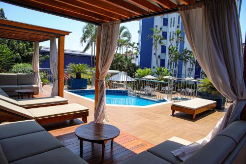 a patio with a pool and a couch and a table at Hotel Portinari Centro in Foz do Iguaçu