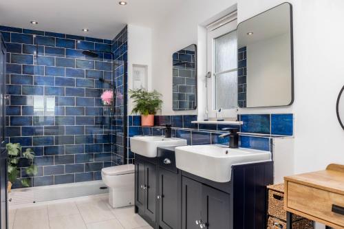 a blue tiled bathroom with two sinks and a toilet at 15 Foster Crescent in Troon