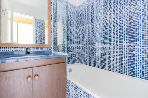 La salle de bains est pourvue de carrelage bleu, d'une baignoire et d'un lavabo. dans l'établissement Résidence le Hameau de Cap Esterel - maeva Home - Appartement 2 pièces 5 personnes - Confort MAE-5344, à Saint-Raphaël