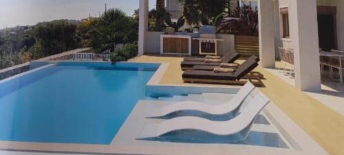 uma piscina com duas espreguiçadeiras e uma casa em Bay Overlook Akrotiri em Korakiaí