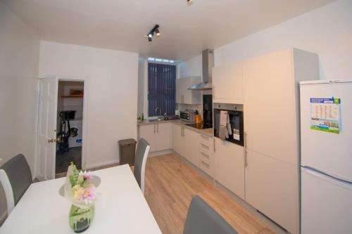 a kitchen with a table and a white refrigerator at Lovely City Home + Free Parking in Manchester