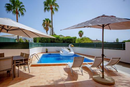 a swimming pool with a swan and a table and umbrellas at Spacious house with pool in Faro