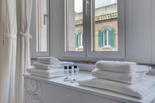 ローマにあるAppartamento Santi Quattro - Colosseoのバスルームのカウンターに座るタオルの山