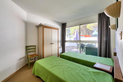 1 dormitorio con 2 camas verdes y ventana en Résidence Saint-Raphaël Valescure - maeva Home - Appartement 3 pièces 6 p 734 en Valescure