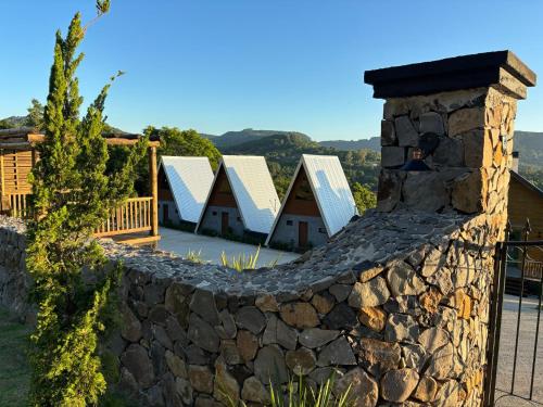 a stone fence with a house in the background at Reserva Linha Bonita in Gramado