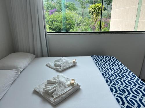 a bed with two towels on it with a window at Pousada Encanto dos Mognos in Ibicoara