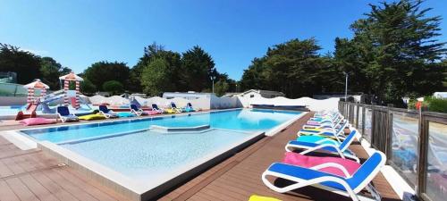 einen Pool mit Liegestühlen und Gartenstühlen in der Unterkunft Mobilhome 4 étoiles - Parc aquatique - eeibci in Le Bois-Plage-en-Ré
