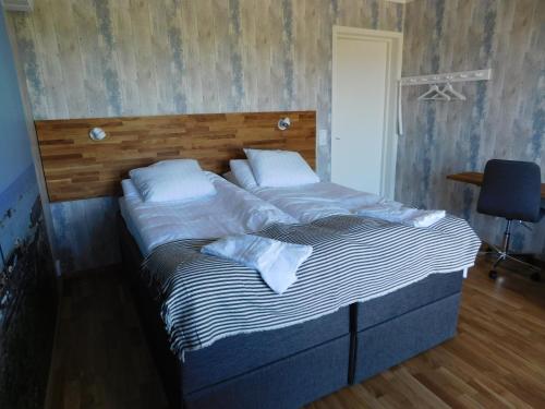a large bed in a bedroom with a wooden headboard at Drottning Ödas Boende in Degerhamn