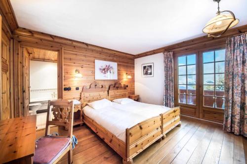 1 dormitorio con 1 cama en una habitación con paredes de madera en Résidence Agathe Blanche - Chalets pour 12 Personnes 984, en Courchevel