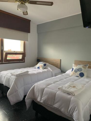 a bedroom with two beds with white sheets and a window at Hotel Bahia in La Paloma