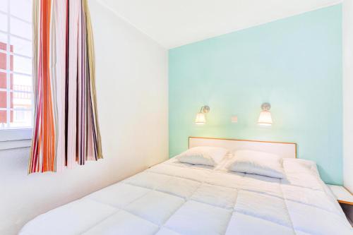 un lit blanc dans une chambre avec une fenêtre dans l'établissement Résidence le Village de Cap Esterel - maeva Home - Appartement 2 pièces 6 personnes - Prestige MAE-5674, à Saint-Raphaël