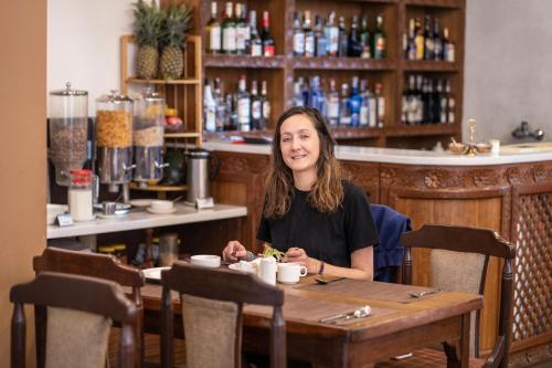 a woman sitting at a table in a restaurant at Hotel Manang - Thamel, Kathmandu in Kathmandu