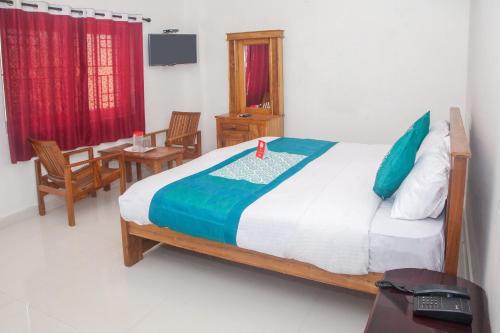 een slaapkamer met een bed en 2 stoelen en een tafel bij Flagship Key 2 Heaven in Ooty