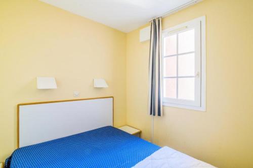 une chambre avec un lit bleu et une fenêtre dans l'établissement Résidence le Hameau de Cap Esterel - maeva Home - Appartement 2 pièces 5 personnes - Confort MAE-5041, à Saint-Raphaël