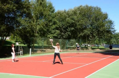 dos chicas jugando al tenis en una pista de tenis en Chalet 3 étoiles - Piscine - eehaed, en Merdrignac