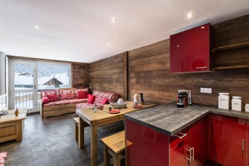 a kitchen and living room with red cabinets and a couch at Résidence La Croix De Verdon - 3 Pièces pour 6 Personnes 394 in Courchevel