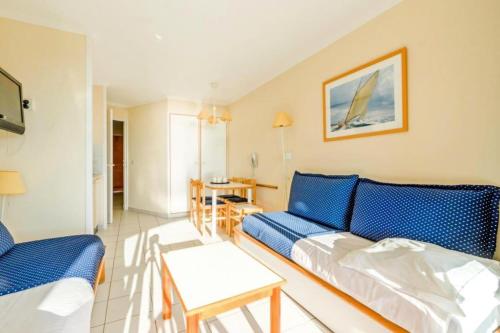 un salon avec un canapé bleu et une table dans l'établissement Résidence le Hameau de Cap Esterel - maeva Home - Studio 5 personnes - Confort MAE-5081, à Saint-Raphaël