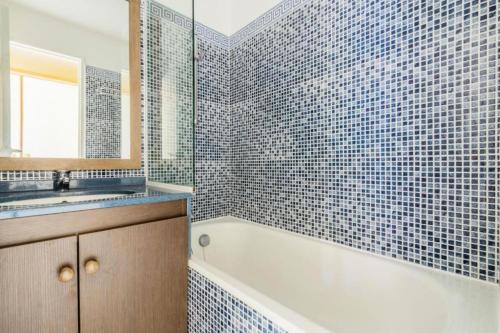 een badkamer met een bad, een wastafel en een spiegel bij Résidence le Hameau de Cap Esterel - maeva Home - Appartement 2 pièces 5 p 571 in Saint-Raphaël