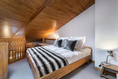 a bedroom with a large bed with a wooden ceiling at Résidence Les Cimes Blanches - Studio pour 5 Personnes 494 in Courchevel