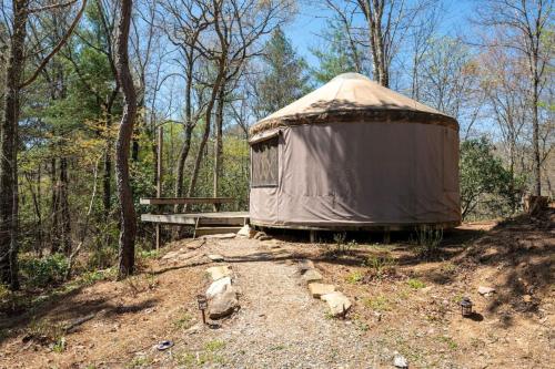 a yurt in the woods next to a wooden bench at Mountain Yurt - Hot Showers in Bryson City
