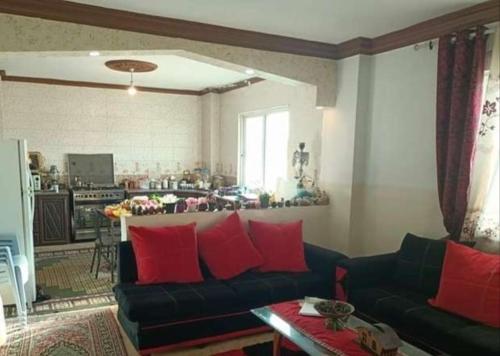 - un salon avec un canapé noir et des oreillers rouges dans l'établissement شقق فندقيه مفروشه شامل الما الكهرباء, à Irbid